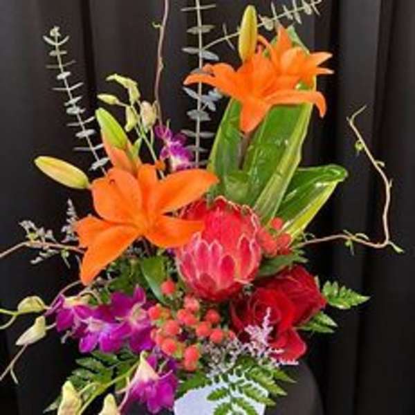 Tropical bouquet with orange lilies and pink protea in a vase