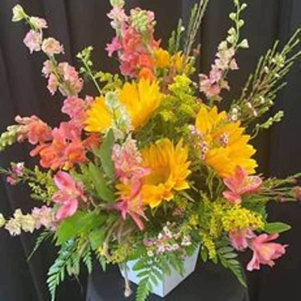 Colorful mixed flower arrangement in a white container