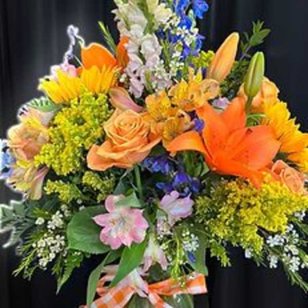 Bright mixed bouquet with orange lilies, roses, and blue flowers