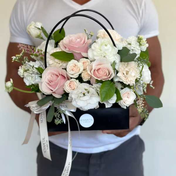 Pink and white roses arranged in a black handled box