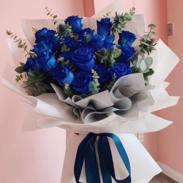 Bouquet of blue roses wrapped in white paper with a blue ribbon