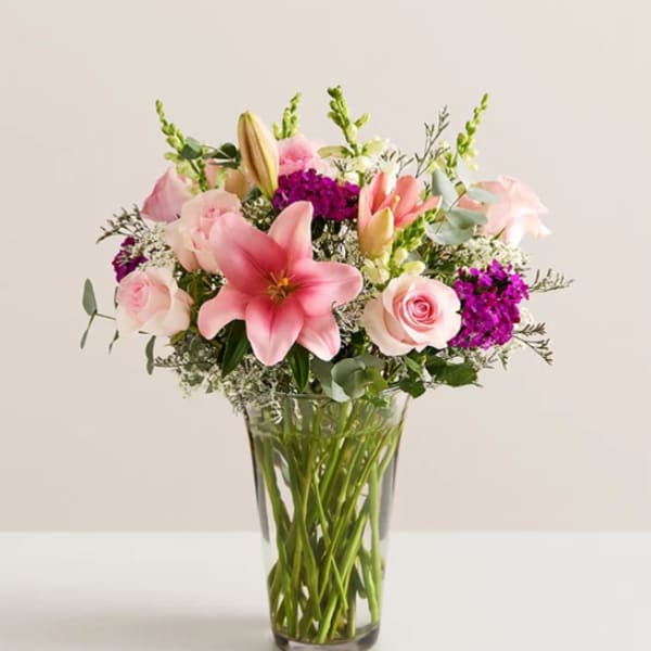 Pink lilies and roses in a clear glass vase