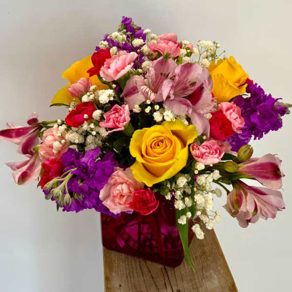 Mixed bouquet with yellow roses, pink and purple flowers in a magenta vase
