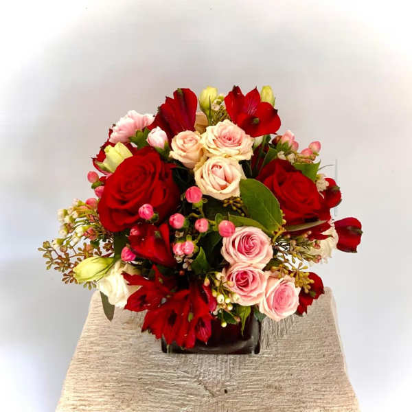 Bouquet of red and pink roses with red blooms in a dark vase