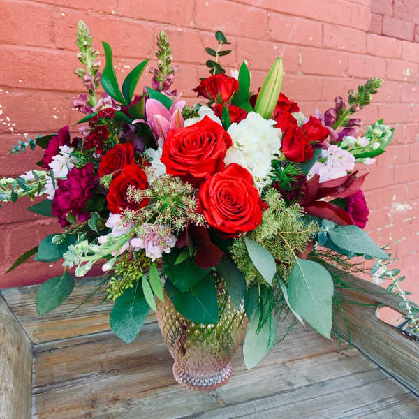 Bouquet of red roses, white blooms, and pink lilies in a glass vase