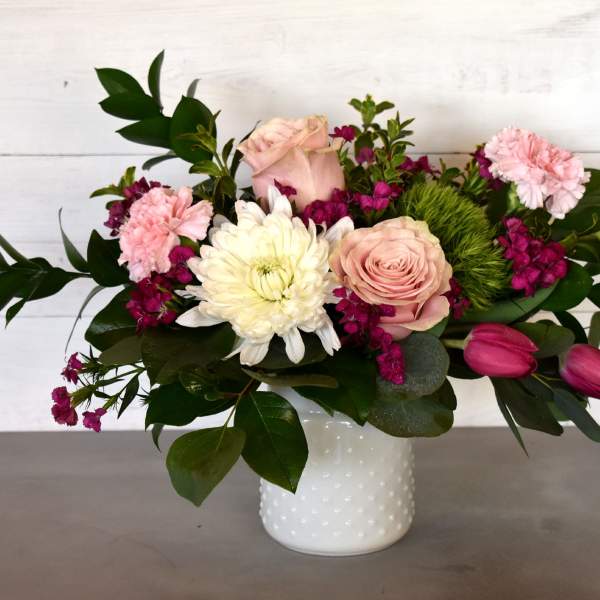 Pink and white flowers arranged in a white vase