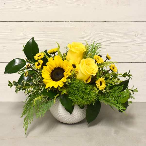 Yellow roses and a sunflower in a white vase