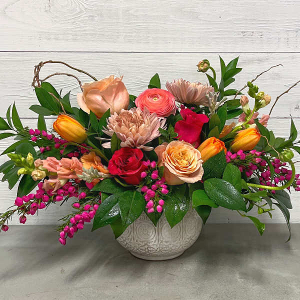 Mixed bouquet in a white ceramic vase with pink, peach, and orange flowers