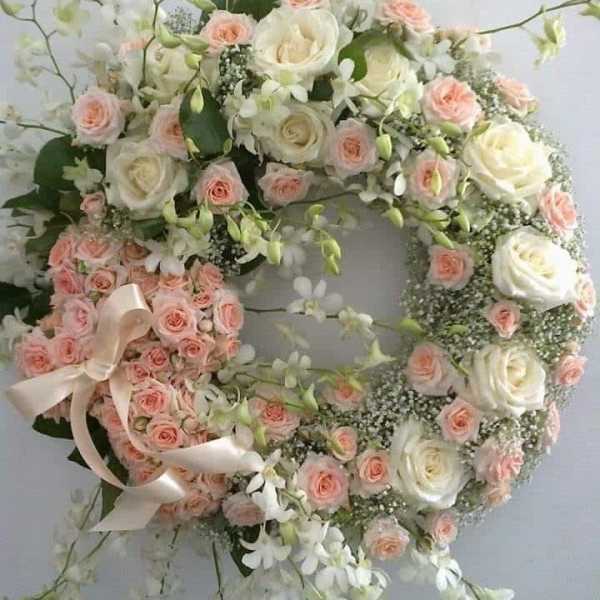 Heart-shaped floral wreath with pink and white roses and ribbon