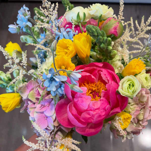 Colorful bouquet with pink peonies, yellow blooms, and blue flowers