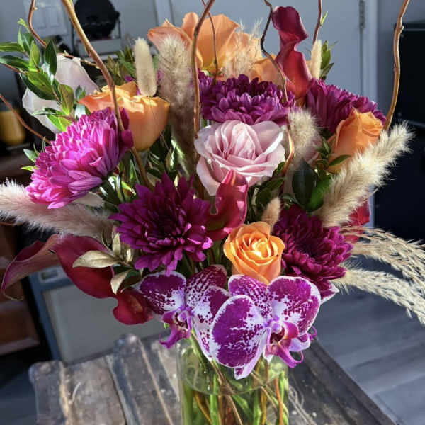 Bouquet of purple, orange, and pink flowers in a glass vase