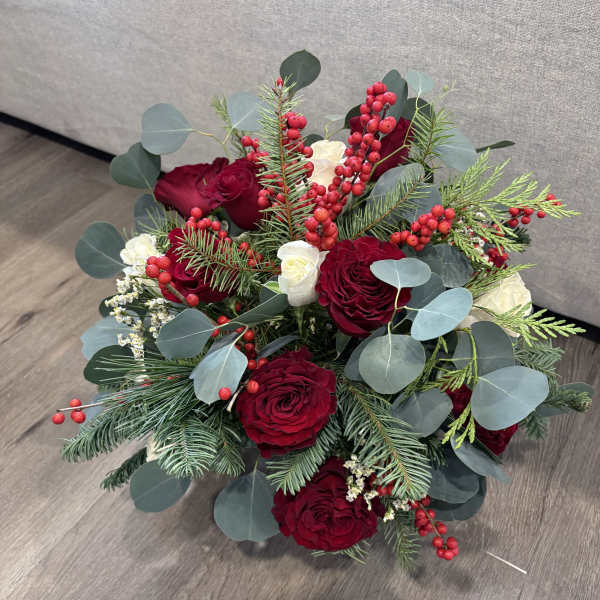 Bouquet of red roses with white blooms, berries, and evergreen foliage