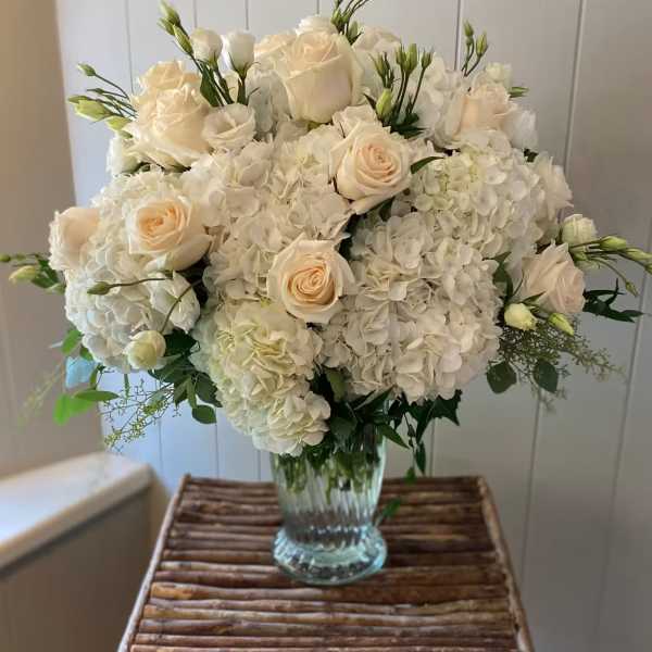 White roses and hydrangeas in a clear glass vase