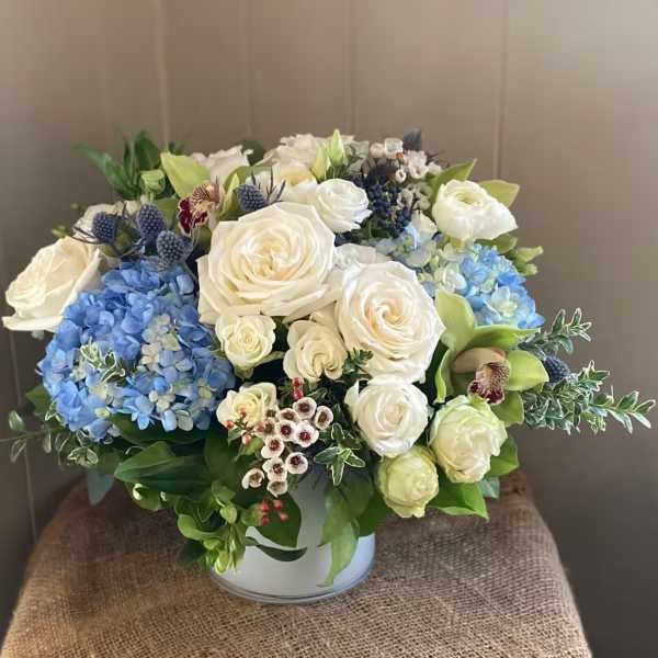 White roses and blue hydrangeas arranged in a low vase