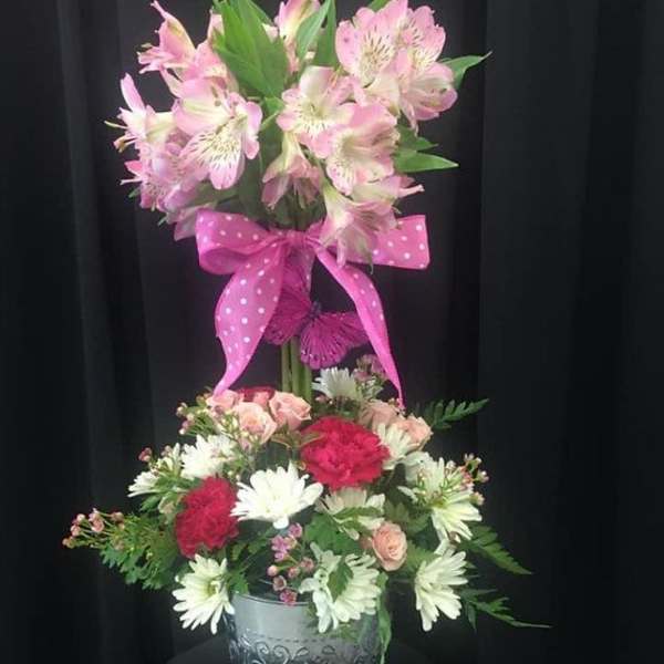 Two-tier floral arrangement with pink lilies and mixed blooms in a metal bucket