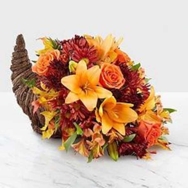 Cornucopia filled with orange and red flowers on a white surface