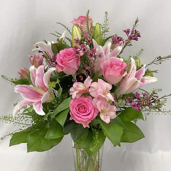 Pink roses and lilies arranged in a clear glass vase