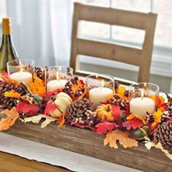 Fall centerpiece with candles, pumpkins, pinecones, and autumn leaves