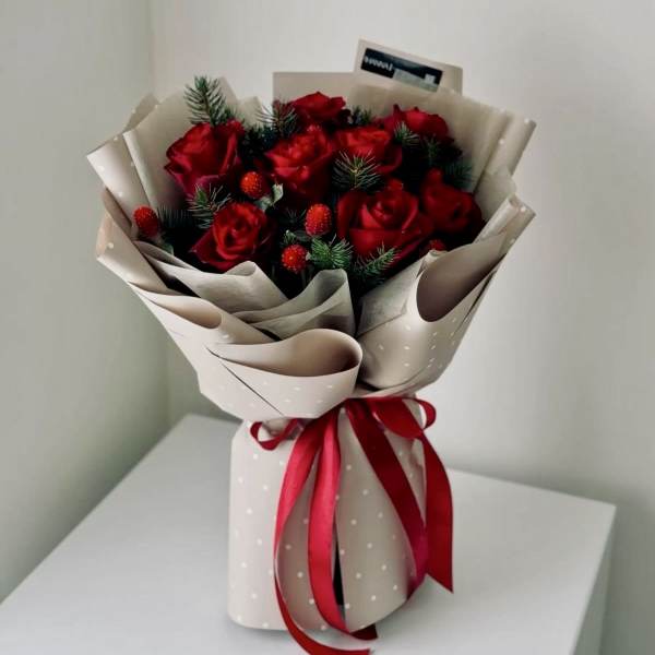 Bouquet of red roses wrapped in beige paper with a red ribbon