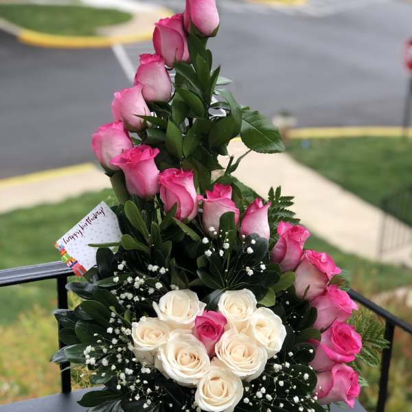 Pink and white roses arranged in a basket with a birthday card