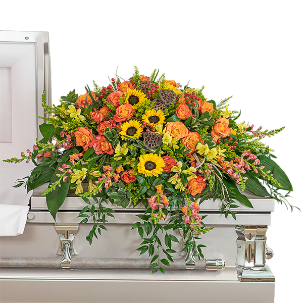 Large orange and yellow floral casket spray on a silver casket