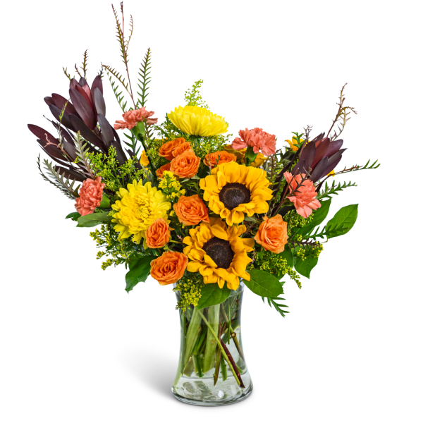 Bouquet of sunflowers, orange roses, and pink carnations in a glass vase