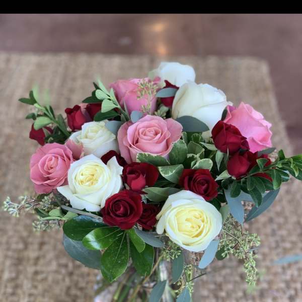 Bouquet of pink, white, and red roses in a glass vase