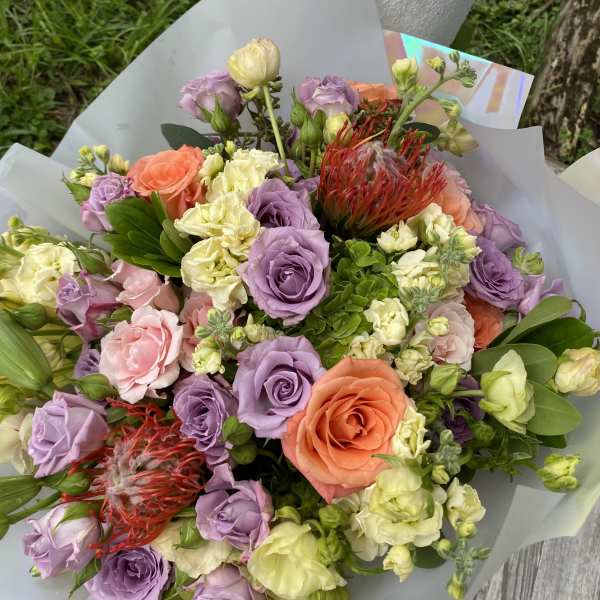 Bouquet of lavender, peach, and pink roses with pale cream blooms
