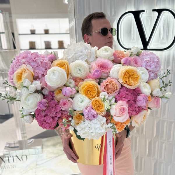 Large bouquet of pink, white, and yellow flowers in a gold box