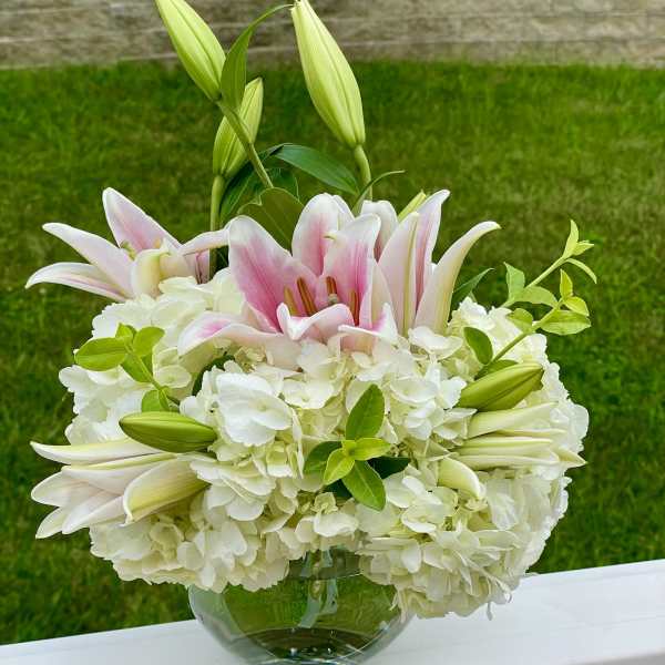 Pink lilies and white hydrangeas in a glass bowl vase