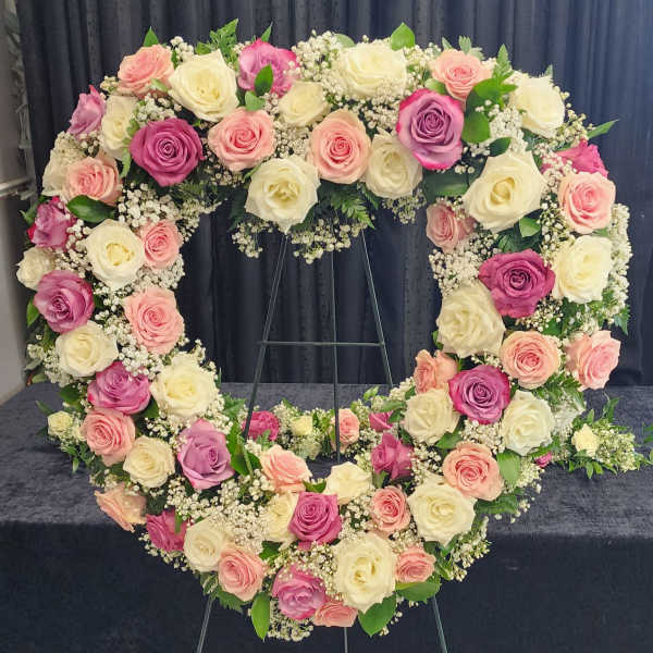 Heart-shaped floral wreath of pink, cream, and lavender roses