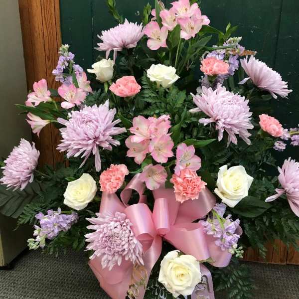 Pink and white floral arrangement with roses, carnations, and lilies in a vase