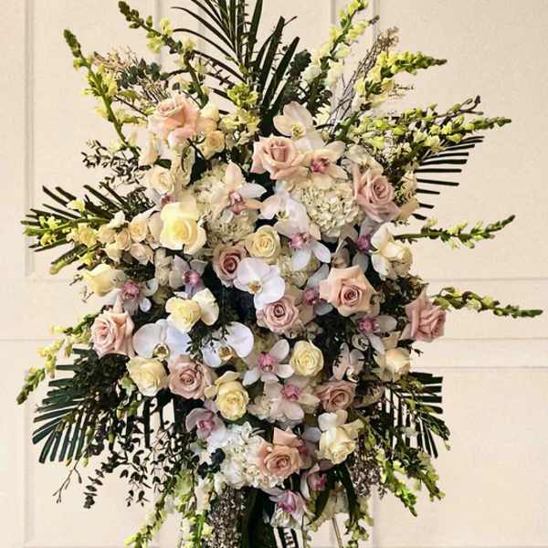 Large standing floral spray with pale roses and orchids on an easel