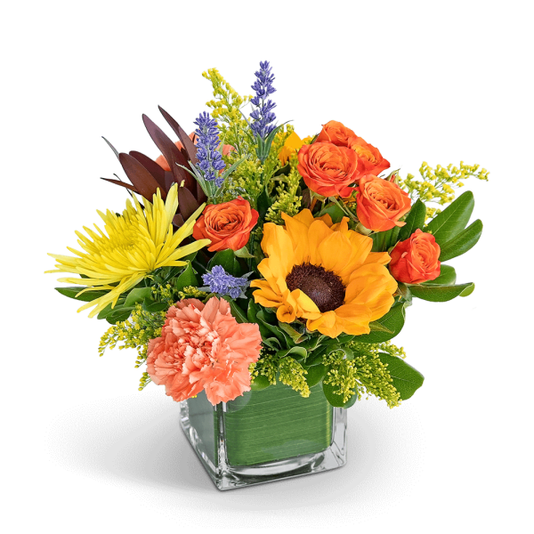 Mixed bouquet in a square glass vase with orange, yellow, and peach flowers
