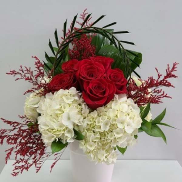 Red roses and white hydrangeas in a white vase