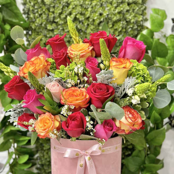 Pink hatbox arrangement of hot pink and orange-yellow roses with white filler flowers