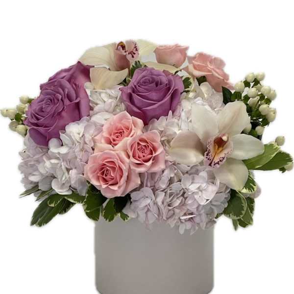 Low pastel arrangement of lavender and pink roses, orchids, and hydrangeas in a white cylinder vase