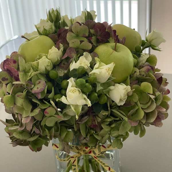 Green hydrangea and white rose arrangement in a clear square vase