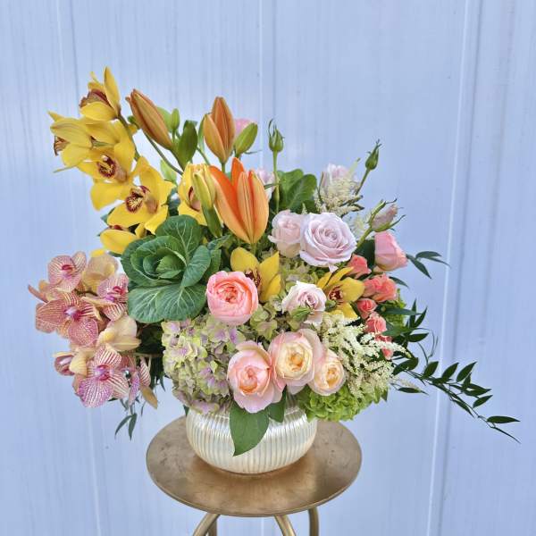 Mixed bouquet in a ribbed white vase with yellow orchids and pink roses