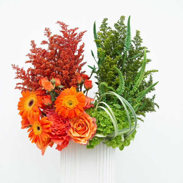 Orange flowers and green foliage arranged in a white vase
