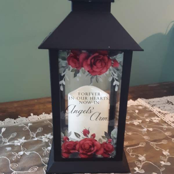 Black lantern with red roses and a memorial message inside