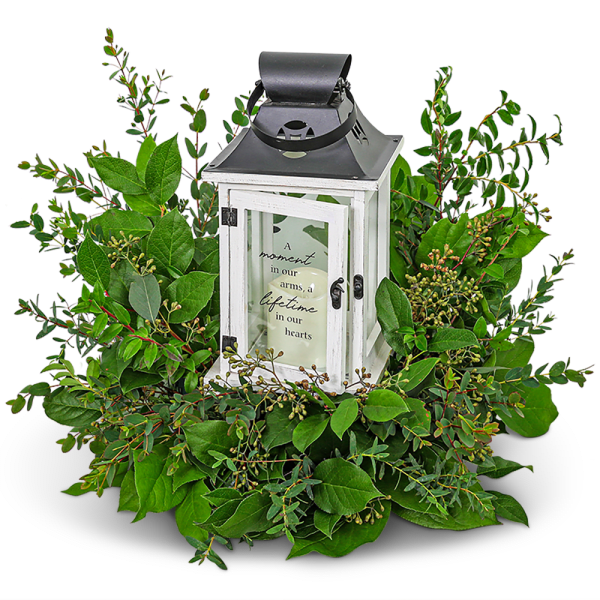 White lantern centerpiece surrounded by green foliage