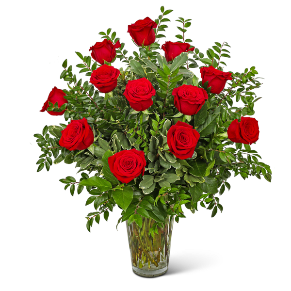 Red roses arranged in a clear glass vase with mixed greenery