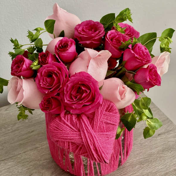 Pink and hot pink roses arranged in a yarn-wrapped vase