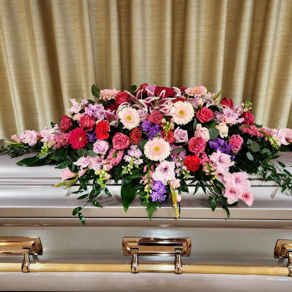 Pink and red floral casket spray on a silver casket