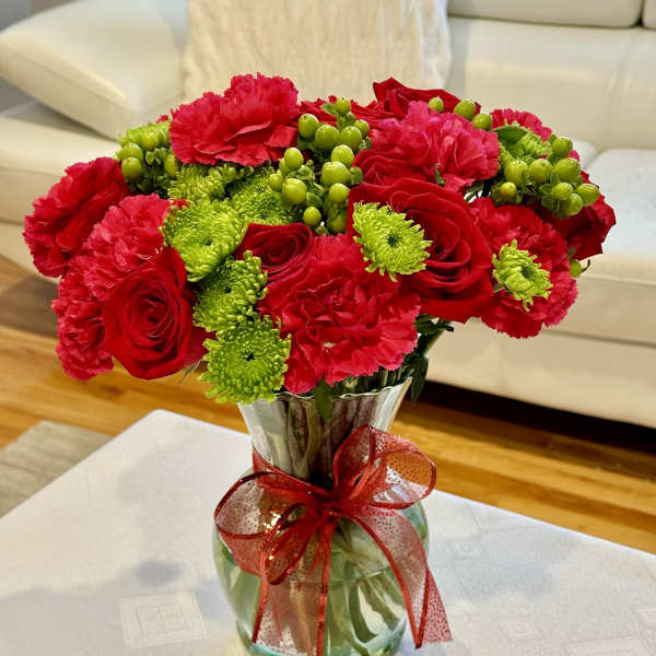 Red roses and pink carnations in a glass vase with a red ribbon