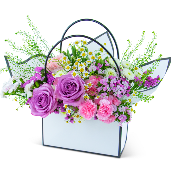 Bouquet of purple roses and pink mixed flowers in a white handled box