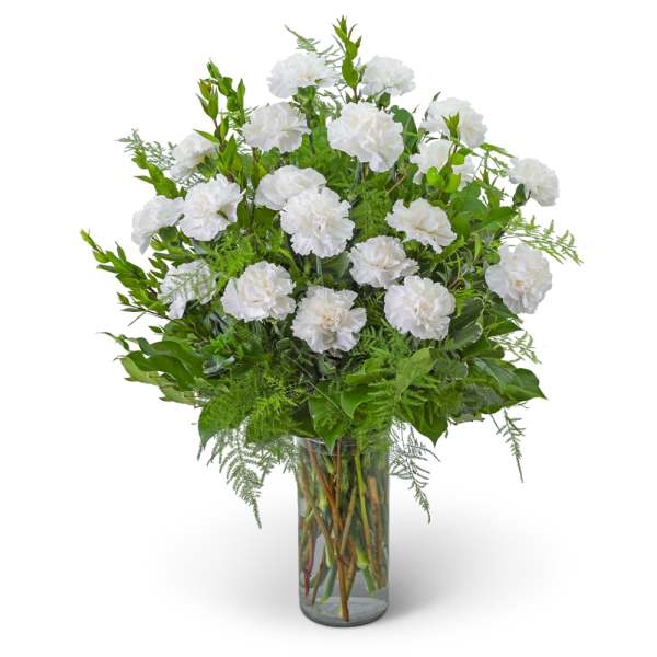 White carnations in a clear glass vase with green foliage