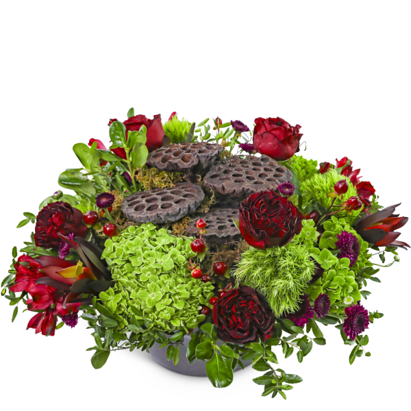 Red and green floral arrangement with lotus pods in a low bowl