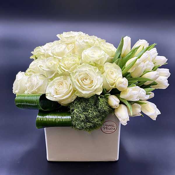 White roses and tulips arranged in a square vase